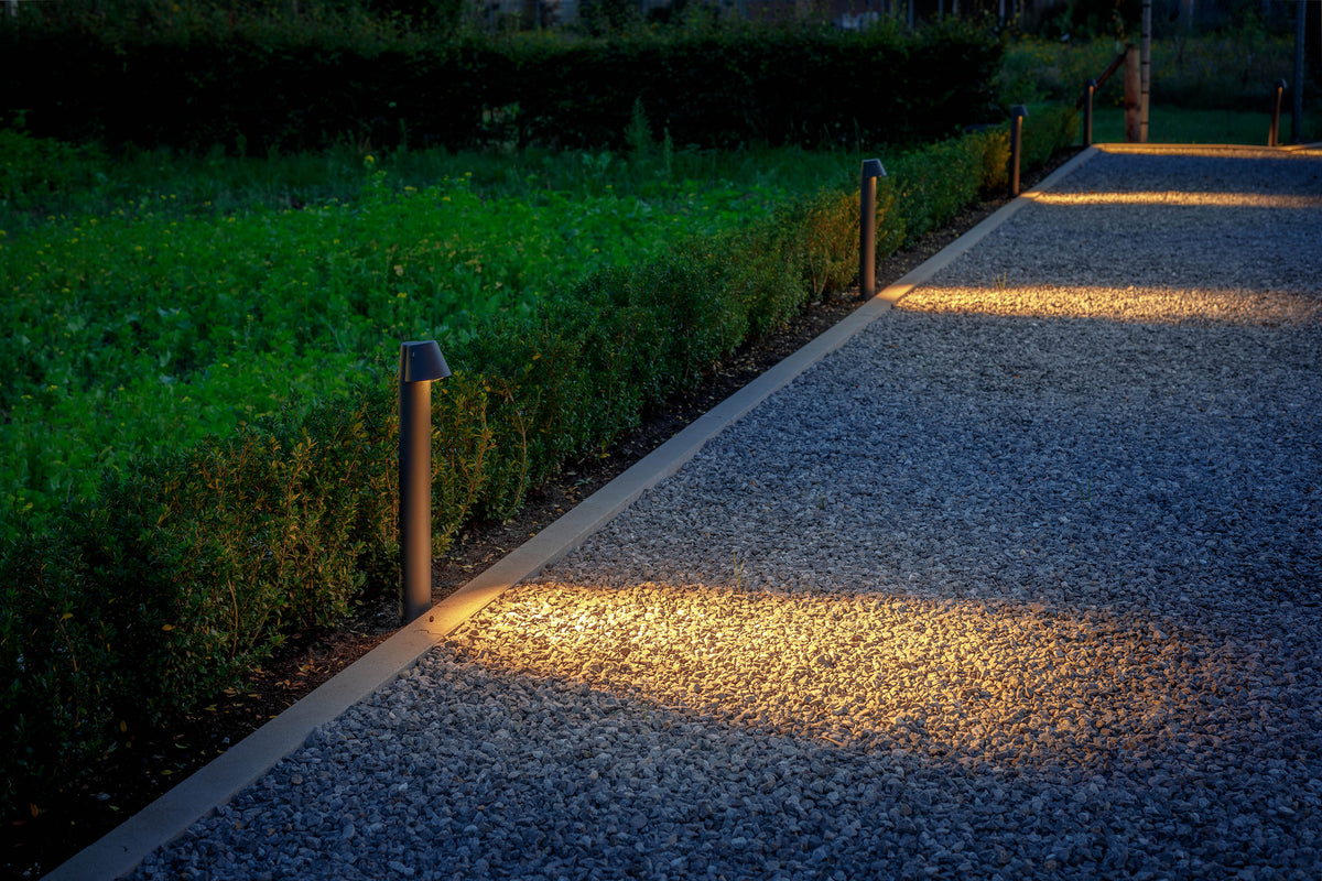Lightpro 12 volt staande buitenlampen verlichten een grindpad langs een haag