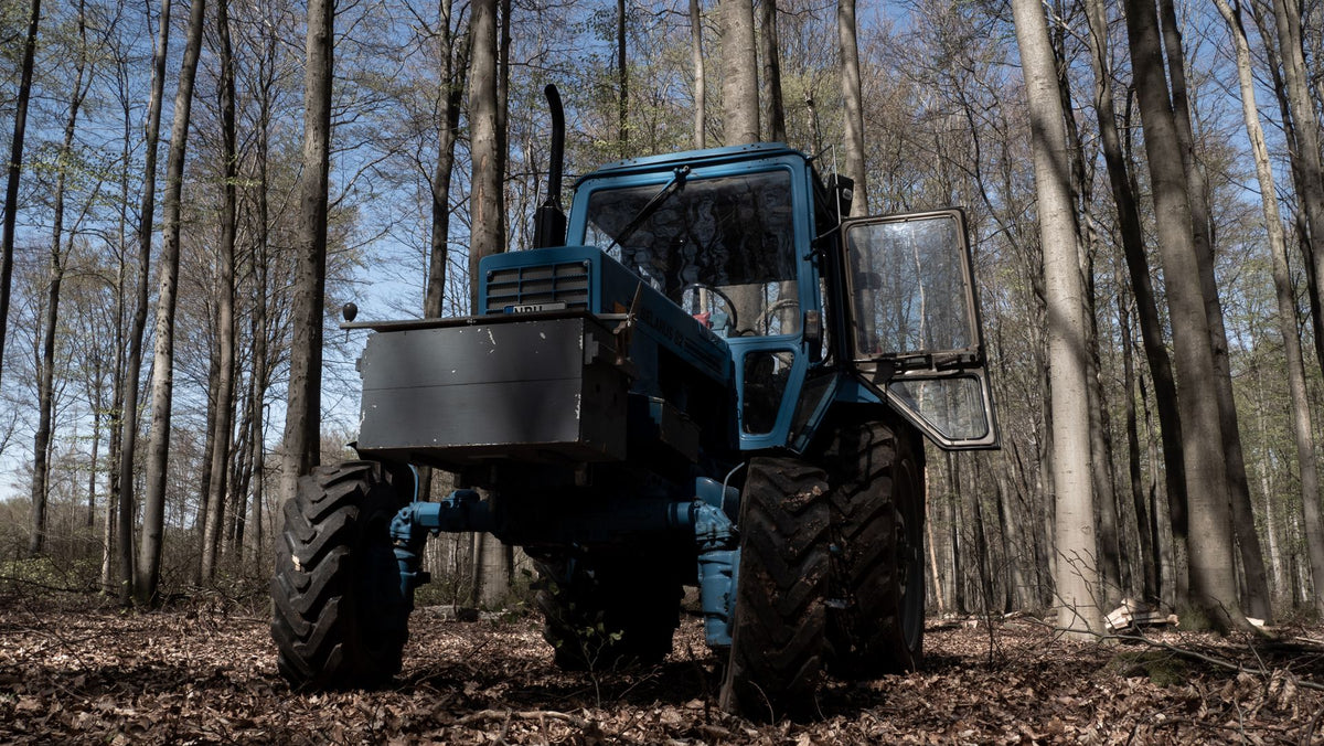 Blauwe tractor in bos bij bosbouwwerk met lier
