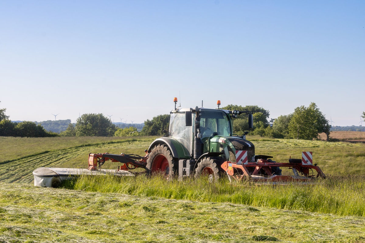 Trekker maait gras met een cirkelmaaier en legt het in een zwad