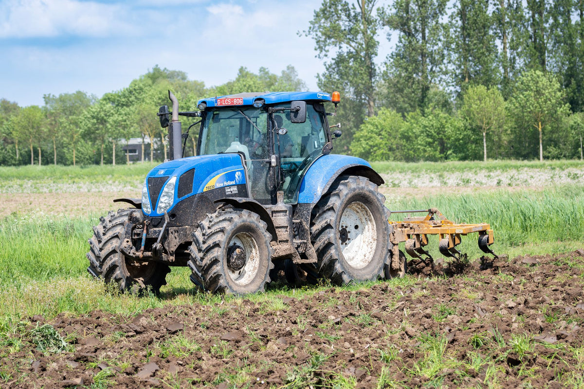 Trekker bewerkt de grond op een Europees perceel