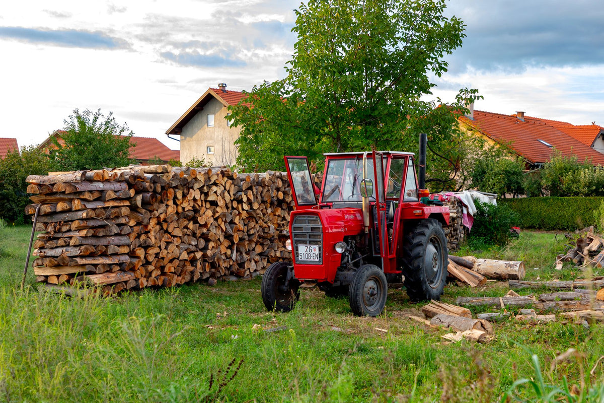 Rode trekker naast stapel brandhout op Europees boerenerf