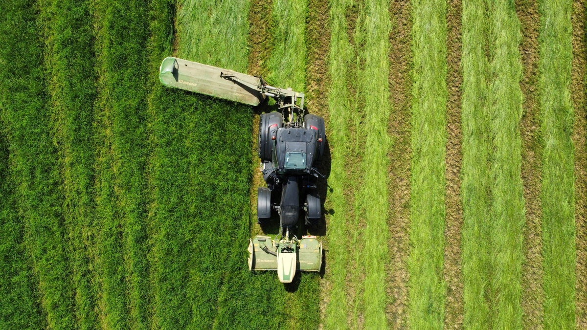 Trekker maait een groen grasperceel, van bovenaf gezien